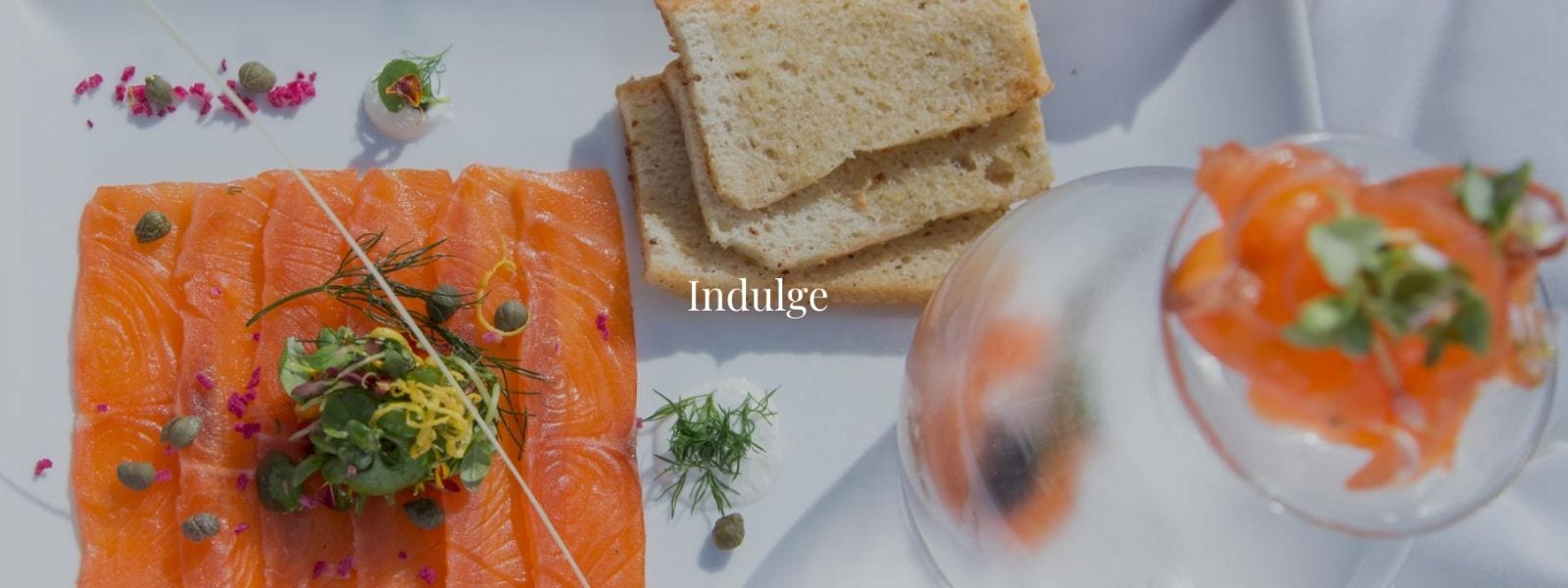 Salmon and bread displayed on a plate with the word Indulge